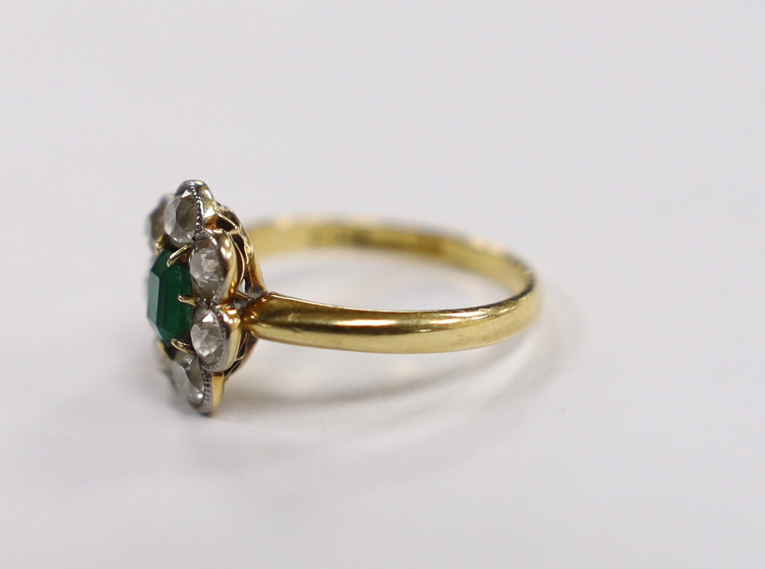 An 18ct, emerald and diamond set circular cluster ring, size L, gross weight 3.3 grams.